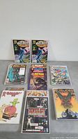 Photo of assorted comic books laid out showing various titles including Batman, Prophet, and others.