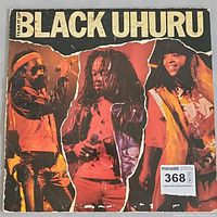Front cover of Black Uhuru Tear It Up vinyl LP showing three band members in performance dress with torn red background.