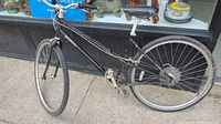 Image of black Norco Cityglide bike showing left side, missing chain, rear multi-speed gears, and pedal crank arm.