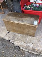 Front view of antique wooden chest showing hinged lid, aged wood surface, and keyhole.