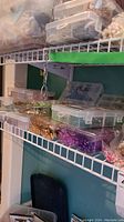 Plastic containers on wire shelf with assorted beads in green, gold, purple, pearl colors