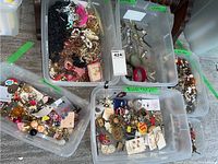 Bins filled with assorted costume jewelry items including earrings, necklaces, brooches, bracelets, and watches