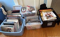 Four bins filled with craft books and materials including embroidery and sewing patterns, displayed on floor