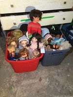 Two large plastic totes filled with dolls of different sizes, styles and hair colours.