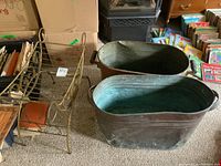 Two copper kettles and metal vanity seat frame arranged with books and boxes in background