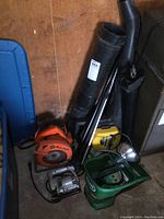 Photo showing Eager Beaver leaf blower with attachments, circular saw, jigsaw, hand seeder, and spotlight grouped together in a corner.