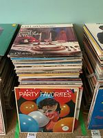 Photo showing large stack of vintage LP records topped with 'The Art of Conducting Wine' and 'Party Favorites' albums