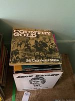 Stack of vintage LP records with visible covers 'Country Gold 24 Current Hits' and 'Jack Bailey'.