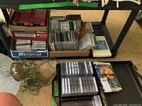 Overview of boxes with cassette tapes, CDs, and VHS tape on floor and under table