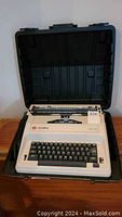 Olympia CE-12 typewriter in open black hard case, showing full keyboard and part of carriage.