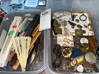 Bin containing eyeglasses, opera glasses, perfume bottles with floral designs, costume rings, pocket tools, and lighters