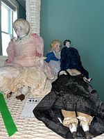 Four dolls arranged on wicker shelf, full group view