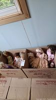Two cardboard boxes holding nine vintage dolls in assorted dresses