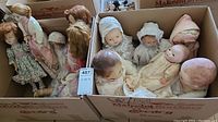 Overall view of a box of vintage dolls showing nine dolls in various conditions ranging from 11 to 16 inches tall.