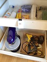 Drawer with disposable cups, plastic wrap, and kitchen accessories in cardboard box