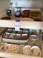 Open drawer showing English bone china tea set items including cups, saucers, and plates arranged in a fabric holder and loose in the drawer.