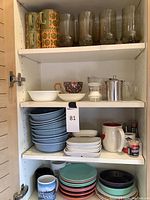 Shelf with Fiesta ceramic mugs, clear and opaque glassware