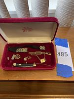 Red velvet jewelry box containing watch, jewelry, earrings, knife, rings and pendant