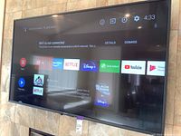 TV powered on showing Android home screen with apps like Netflix, Disney+, YouTube