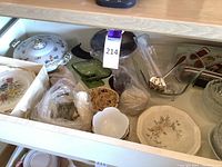 Drawer containing assorted china, glass serving and decorative items, including covered serving dish and floral plates in box.
