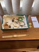Overall view of the box containing watches, pins, chain, thimbles, and assorted jewelry.