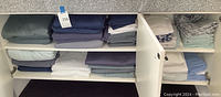Interior of cabinet with folded sheets and pillowcases on three shelves