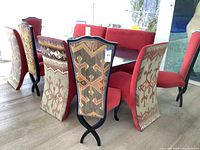 Set of nine red velvet dining chairs around a table, showing embroidered fabric backs and dark wood frames
