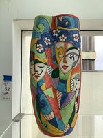 Frontal view showing full decorative faces motif and glossy surface