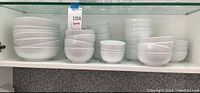 Six stacks of white bowls in three distinct sizes on a shelf