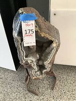 Front view of geode mounted on iron stand, showing overall shape and stand support