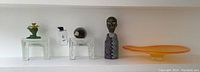 Overview of two glass block decor pieces, pottery bust and palette bowl on white shelf
