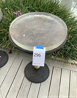 Close elevated view of round tabletop showing worn metal surface under clear glass