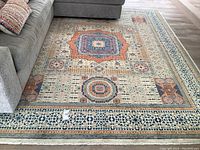 Full view of multicolored Persian rug laid under sofa showing overall pattern and condition