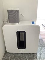 White Sonos One speaker on top of white Sonos Sub subwoofer.