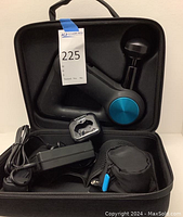 Theragun massage gun inside open carrying case with power adapter, small pouch, and charging dock