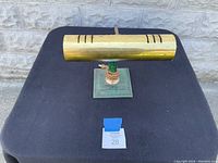 Front angled view of the bankers lamp showing the brass shade and green base with wrapped cord section.