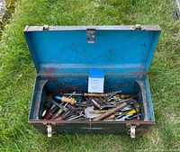 Open metal Craftsman tool box showing a variety of hand tools inside, visible rust and wear on the box and tools.