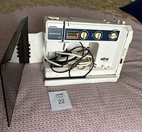 Front and side view of the Elna Air Electronic SU sewing machine showing control dials, stitch pattern chart, and attached power cord.