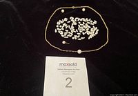 Photo showing a collection of irregular freshwater loose pearls arranged in a cluster, two round saltwater pearls near the top, one saltwater pearl attached to a fine gold chain in an oval form, and an additional saltwater pearl with an earring post but missing the backing, all laid out on a black background.