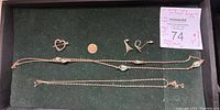 Overview of jewelry lot in green case with heart pin, round charm, earrings, and two necklaces.