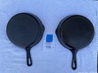 Lot of two cast iron skillet pans, showing top view with handles and pouring spouts.