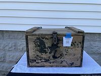 Front view of the Hood branded wooden milk crate showing aged black paint, metal latch on top and front panel wear.