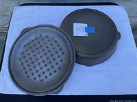 Image showing the bottoms of the pan and lid placed upside down on a white mat outdoors, highlighting the raised circular pattern on the pan bottom and the lid's flat underside.