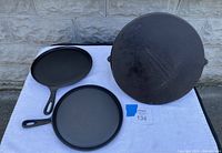 Top view of all three cast iron griddles on display showing two smaller handled griddles and one larger griddle.