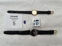 Two wristwatches and opal doublet stones on white fabric background.