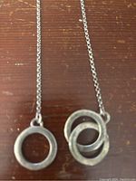 Silver chain necklace with two circular pendants laid flat on a wooden surface
