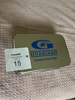 Guardian brand tin box with blue logo and Seasons Greetings print used for storage