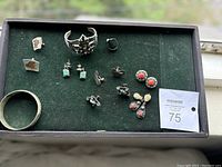 Wide shot showing full collection of vintage sterling silver jewelry including bracelets, rings, various earrings with stones.