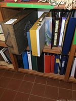 Shelf with various boxes, binders, and photo albums, including a wooden box and yellow/gray box with handle.