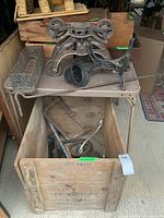 View of wooden crate with Crown Cork & Seal Co. stamp showing crate open with various antique metal items inside and on a table above it.